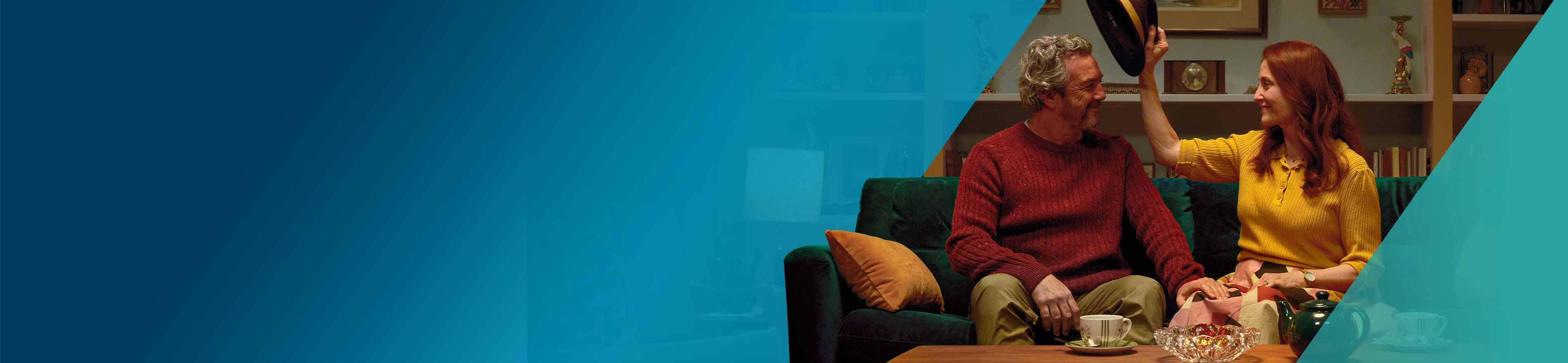 Actor portrayal of an OPDIVO Qvantig™ patient sitting on a couch with a women as she removes his hat.